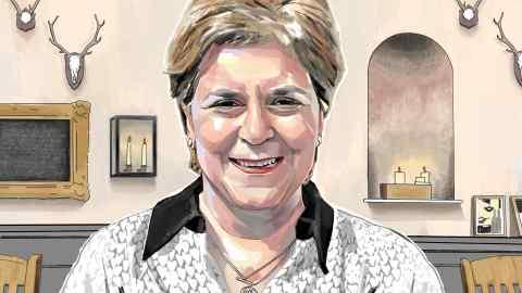 A woman with short blonde hair in a pale shirt with black collar sits in a restaurant with pale walls that sport antlers and candles